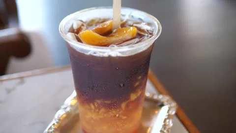 Iced peach coffee in a plastic cup with straw on table in cafe Stock Footage 320768942