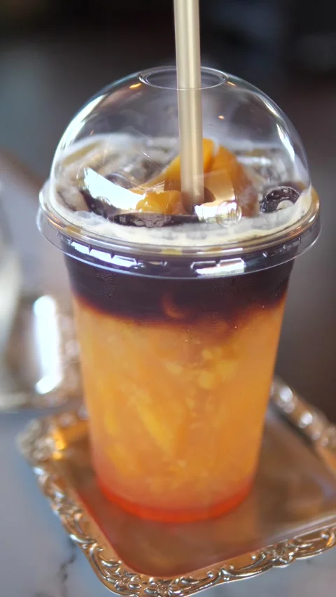 Iced peach coffee in a plastic cup with straw on table in cafe Stock Footage 320768945