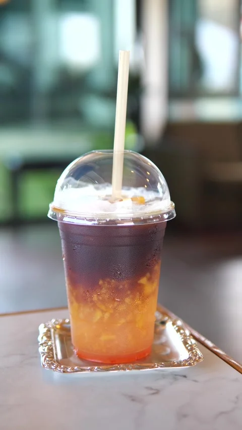 Iced peach coffee in a plastic cup with straw on table in cafe Stock Footage 320768950