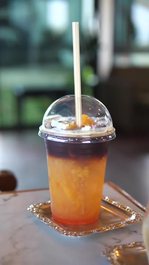 Iced peach coffee in a plastic cup with straw on table in cafe Stock Footage 320768965