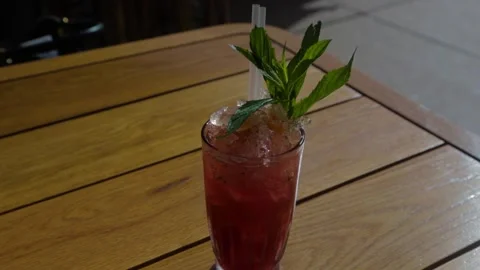 Iced Red Drink with Mint Garnish on Wooden Table at Outdoor Sydney Bar Stock Footage 345806369