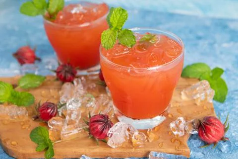 Iced roselle tea glass with fresh roselle fruit on wooden table for healthy h Foto stock