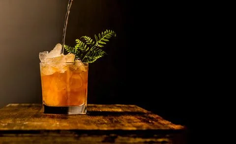 Iced tea with crashed ice in a transparent glass isolated over dark black Stock Photos