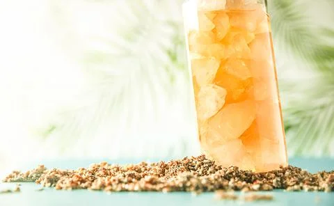 Iced tea with crashed ice in a transparent tall glass on tropical background Stock Photos