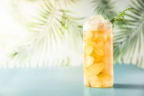 Iced tea with crashed ice in a transparent tall glass on tropical background Stock Photos