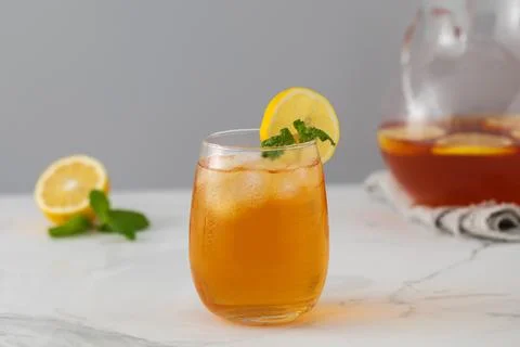 Iced tea with lemon and mint in a glass and in a jug. Summer drinks. Stock Photos