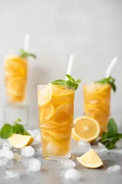 Iced tea with lemon, ginger and mint in tall glasses on gray background Stock Photos