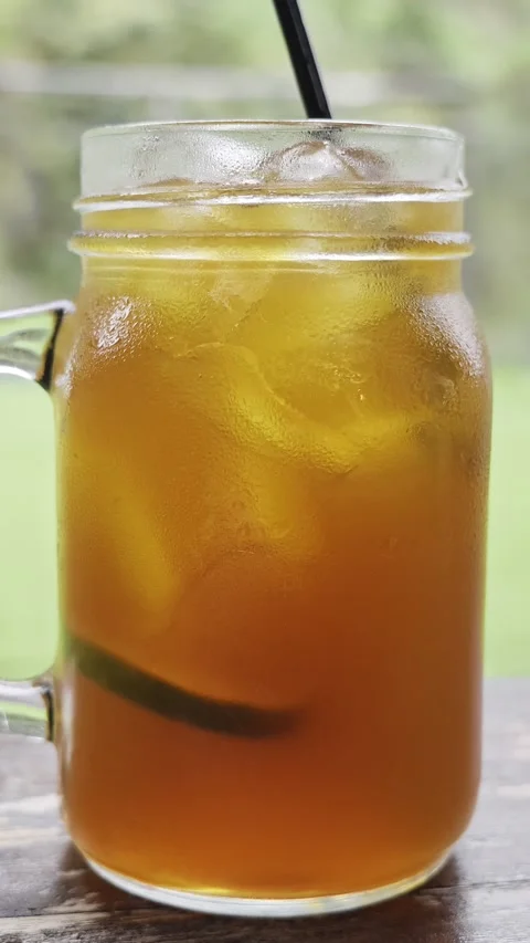 Iced tea with lime slice in glass mason jar mug with straw Stock-Footage 347214616