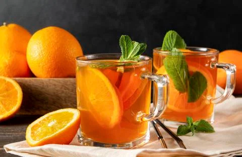 Iced tea with orange and mint, fresh oranges on a towel on a dark wooden Stock Photos
