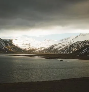 Iceland dramatic sky with snow capped mountain at ocean lake water. Southern Stock Photos