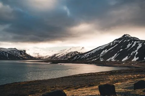 Iceland dramatic sky with snow capped mountain at ocean lake water. Southern Stock Photos
