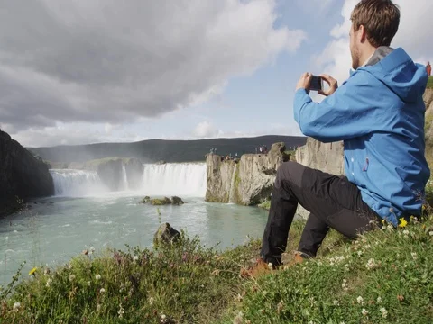 Iceland tourist taking photo of waterfall Godafoss using smart phone camera Stock Footage