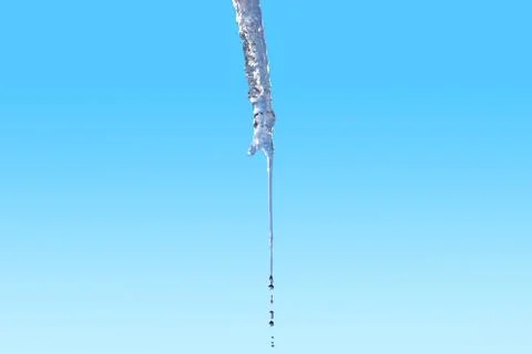Icicle melts with falling drops on a background of blue sky on a bright spri Stock Photos