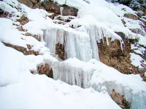 Icicle at a small waterfall on a rocks wall Stock Photos