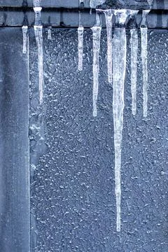 Icicles against a gray wall Stock Photos