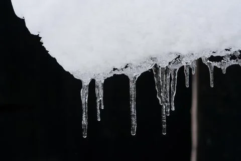 Icicles on black background. Winter concept. Melting icicles. Stock Photos