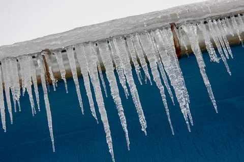 Icicles on a blue wall background. Stock Photos