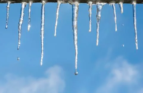 Icicles with drops on blue sky Stock Photos
