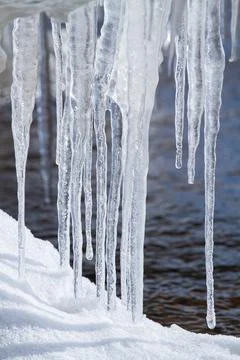 Icicles hang on the river bank Stock Photos