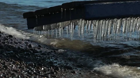 Icicles hanging over the water. Waves on lake Baikal, Siberia, wooden pier. Stock Footage 86434174