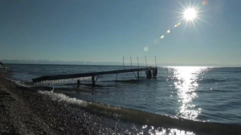 Icicles hanging over the water. Waves on lake Baikal, Siberia, wooden pier. Stock Footage 86434302