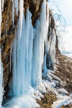 Icicles hanging from a rocks on ocean shore Stock Photos