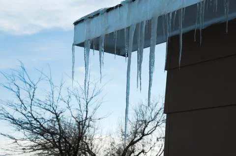 Icicles hanging from rooftop, tree Stock Photos