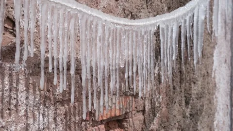 Icicles hanging from a rope outdoors in cold winter weather mountain scene Stock Footage 346239379