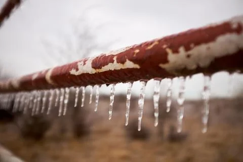 Icicles hanging from a rusty old pipe or pole Foto stock