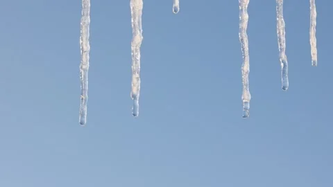 Icicles melt against a clear blue sky. Close-up. Video stock 328580602