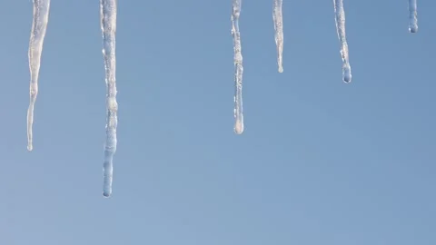 Icicles melt against a clear blue sky. Close-up. Video stock 328580605