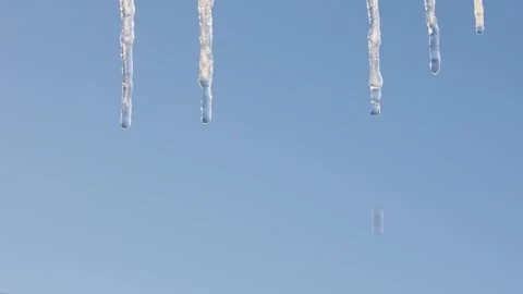 Icicles melt against a clear blue sky. Close-up. Video stock 328580688