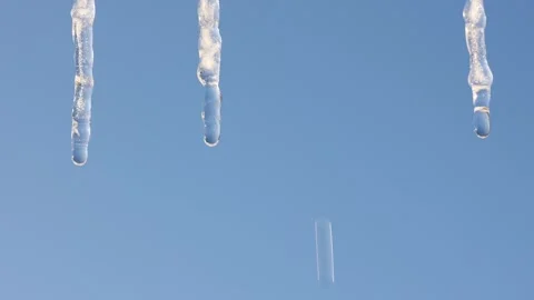 Icicles melt against a clear blue sky. Close-up. Video stock 328581253