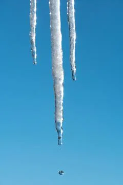 Icicles melt and drip in the spring against the blue sky.Meteorology, global  Stock Photos