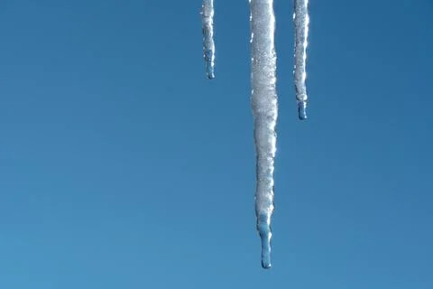 Icicles melt and drip in the spring against the blue sky.Meteorology, global  스톡 사진