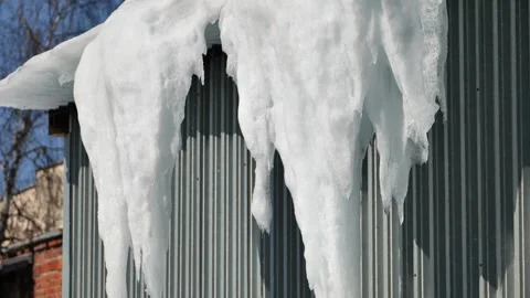 Icicles melting on a metal wall, casting shadows, indicating a change of season Stock Footage 337825555