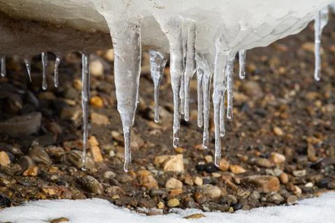 Icicles on a pebble beach Stock Photos