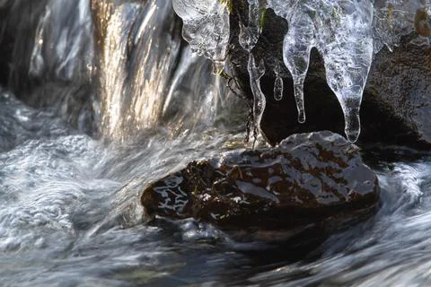 Icicles on rocks in a fast stream Stock Photos