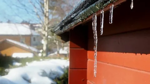 Icicles smelting at closeup of red building under blue sky Stock Footage 87266423