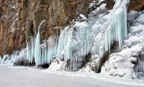 Icicles of splashed ice on steep rock Stock Photos
