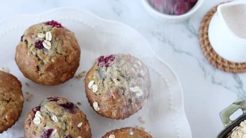 Icing sugar falling on vegan raspberry oatmeal muffins, top view Stock Footage 266927764