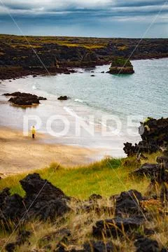 Iclandic landscape sea shore with a man in yellow coat Stock Photos