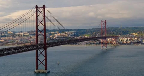 The iconic 25 de Abril Bridge stretches across Tagus River in Lisbon, Portugal Stock Footage 309654493