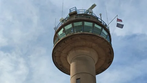 Iconic coastguard tower with radar and flags against a cloudy sky Stock Footage 342404996