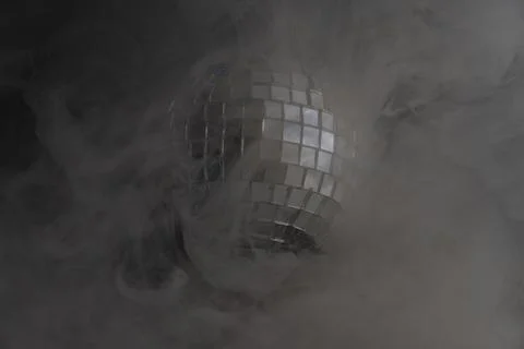 Iconic image showcasing a disco ball amidst thick smoke, reflecting light thr Stock Photos
