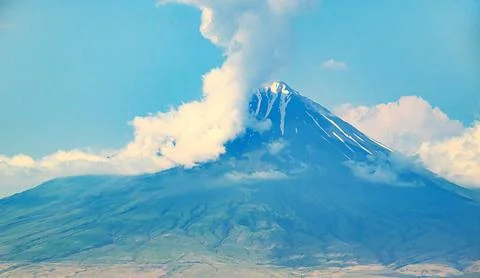 Iconic mountain with snow-capped summit, surrounded by clouds Stock Photos