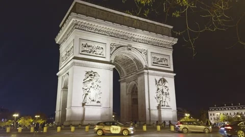 Iconic neoclassical Arc de Triomphe illuminated at night with traffic and urban Stock Footage 324885865