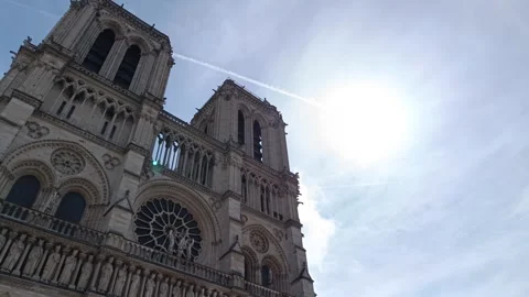 The iconic Notre Dame de Paris Cathedral against a bright sun and blue sky Stock Footage 341966515