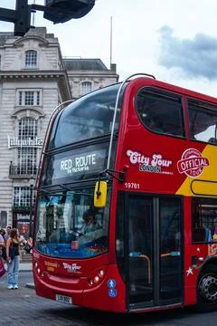 Iconic red double-decker bus driving through historic London city street Foto stock