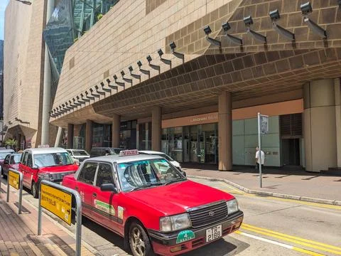 Iconic red taxis queue at a stand on a bustling commercial street in downtown Foto stock
